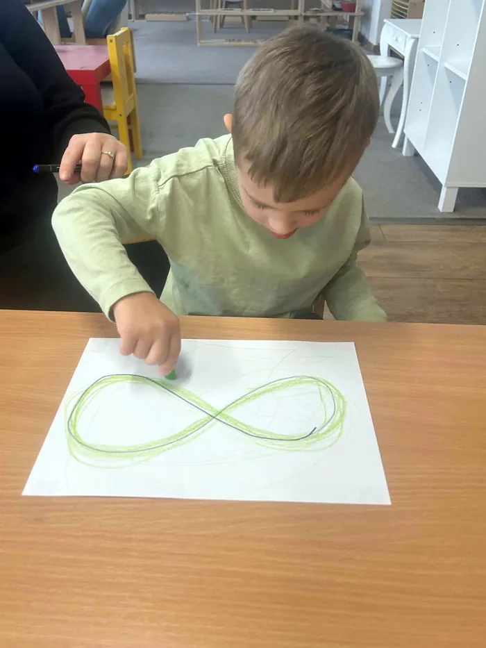 Chlapec kreslí na papier ležatú osmičku